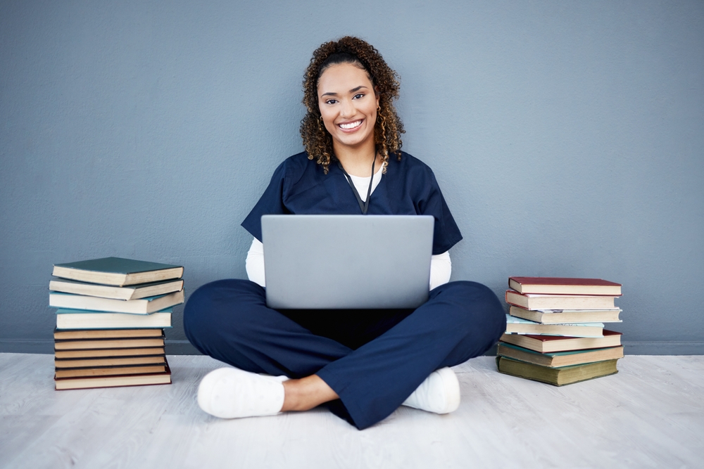 Rockhurst Online nursing student studying for NCLEX exam at laptop next to textbooks