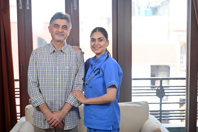 A smiling nurse stands next to a patient.